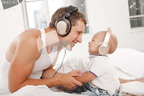 Image of young father with his nine months old som on the bed at home