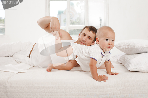 Image of young father with his nine months old son on the bed at home