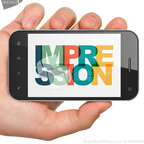 Image of Marketing concept: Hand Holding Smartphone with Impression on  display