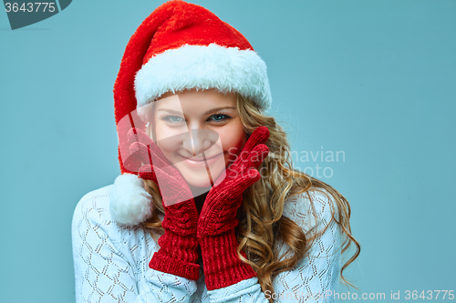 Image of The happy girl dressed in santa hat. Holiday concept with blue background.