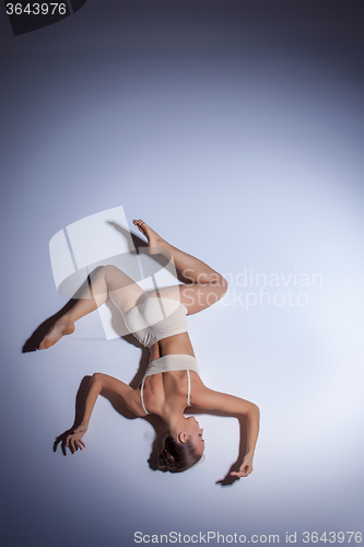 Image of Young beautiful dancer in beige swimwear dancing on lilac background