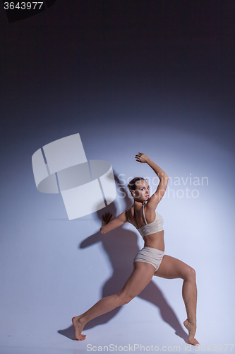 Image of Young beautiful dancer in beige swimwear dancing on lilac background