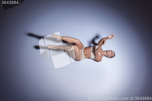 Image of Young beautiful dancer in beige swimwear dancing on lilac background