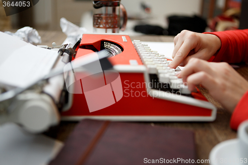 Image of woman at table typing on typewriter