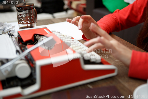 Image of woman at table typing on typewriter