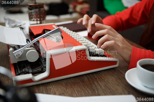 Image of woman at table typing on typewriter