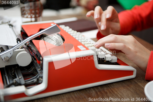 Image of woman at table typing on typewriter