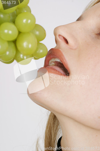 Image of Young woman eating grapes