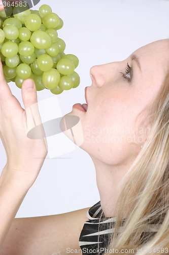 Image of Young woman eating grapes