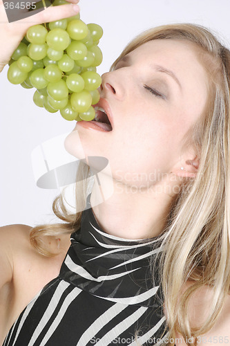 Image of Young woman eating grapes