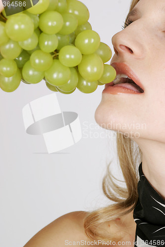 Image of Young woman eating grapes