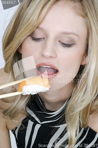 Image of Young woman eating sushi