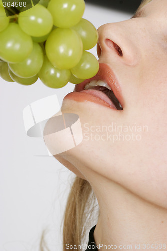 Image of Young woman eating grapes