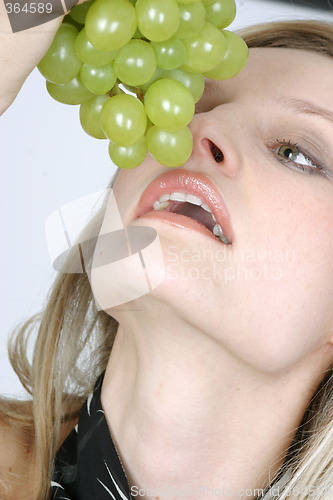 Image of Young woman eating grapes