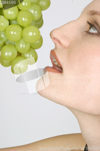 Image of Young woman eating grapes