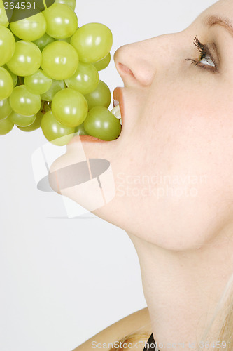 Image of Young woman eating grapes