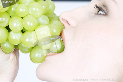 Image of Young woman eating grapes