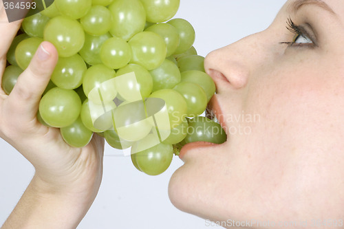 Image of Young woman eating grapes
