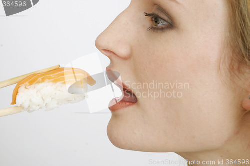 Image of Young woman eating sushi
