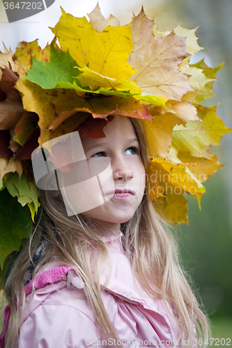Image of funny smiling girl in maple leaves wreath on her head