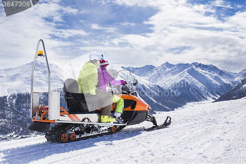 Image of Young couple riding snowmobile snow mountain road