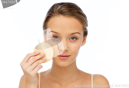 Image of young woman cleaning face with exfoliating sponge