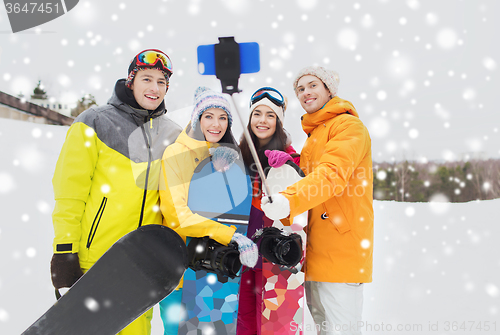 Image of happy friends with snowboards and smartphone