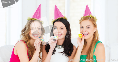 Image of three smiling women in hats blowing favor horns