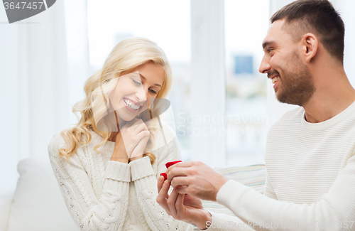 Image of happy man giving engagement ring to woman at home