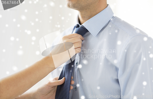 Image of close up of woman hands adjusting tie on mans neck