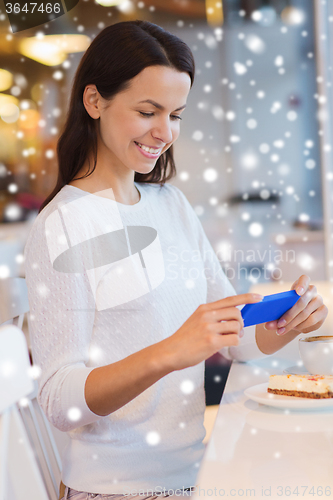 Image of smiling woman with smartphone and coffee at cafe