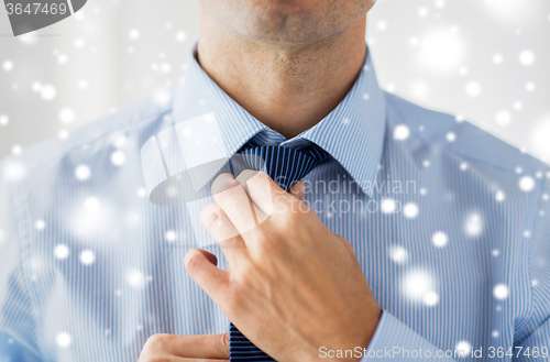 Image of close up of man in shirt adjusting tie on neck