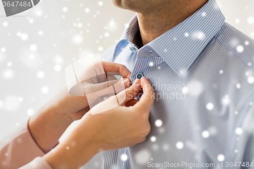 Image of close up of man and woman fastening shirt button
