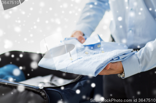 Image of businessman packing clothes into travel bag