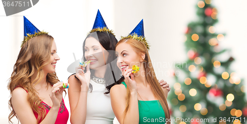 Image of three smiling women in hats blowing favor horns