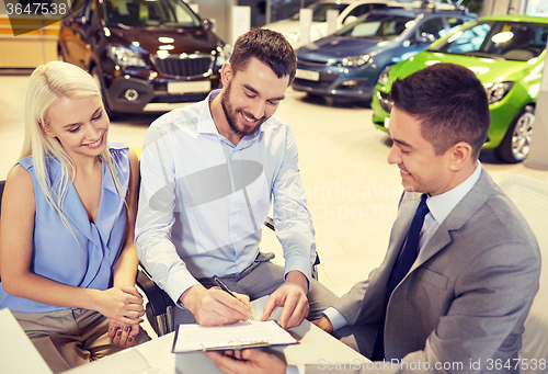 Image of happy couple with car dealer in auto show or salon