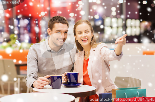 Image of happy couple with shopping bags drinking coffee