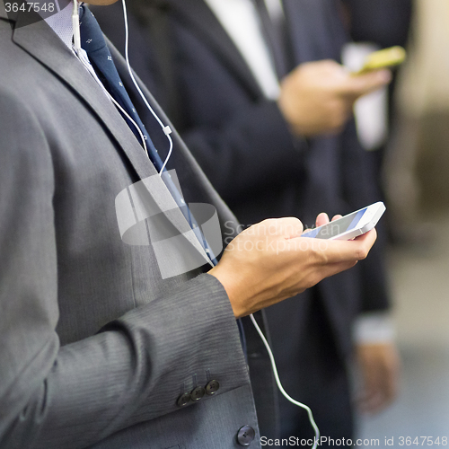 Image of Businessmen using their cell phones on subway.