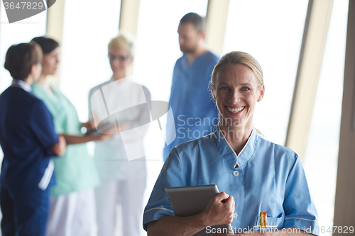Image of female doctor with tablet computer  standing in front of team