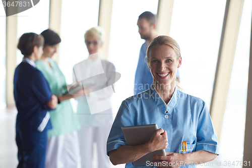 Image of female doctor with tablet computer  standing in front of team