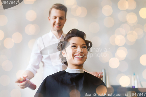 Image of happy woman with stylist making hairdo at salon