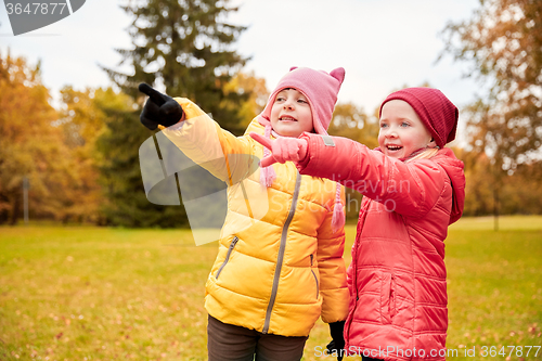 Image of happy little girls pointing finger in autumn park