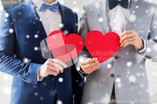 Image of close up of male gay couple holding red hearts