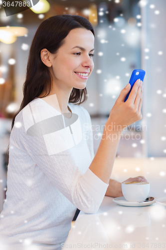 Image of smiling woman with smartphone and coffee at cafe