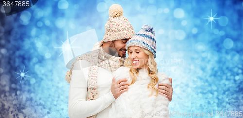 Image of happy couple in winter clothes hugging over lights