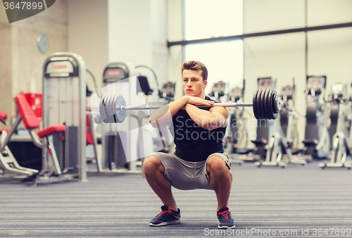 Image of young man flexing muscles with barbell in gym