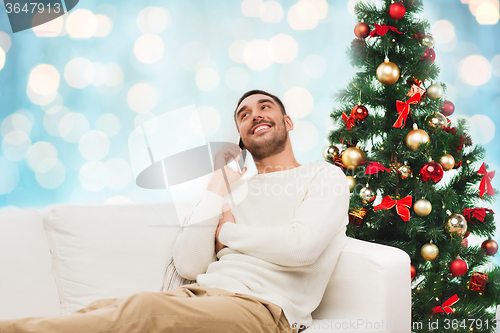 Image of man calling on smartphone over christmas lights