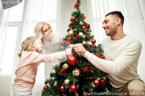 Image of happy family decorating christmas tree at home