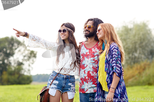 Image of smiling young hippie friends on green field