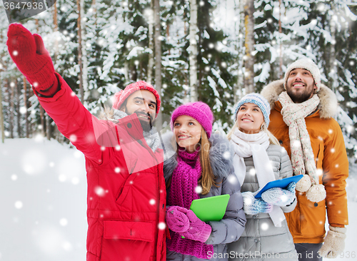 Image of smiling friends with tablet pc in winter forest